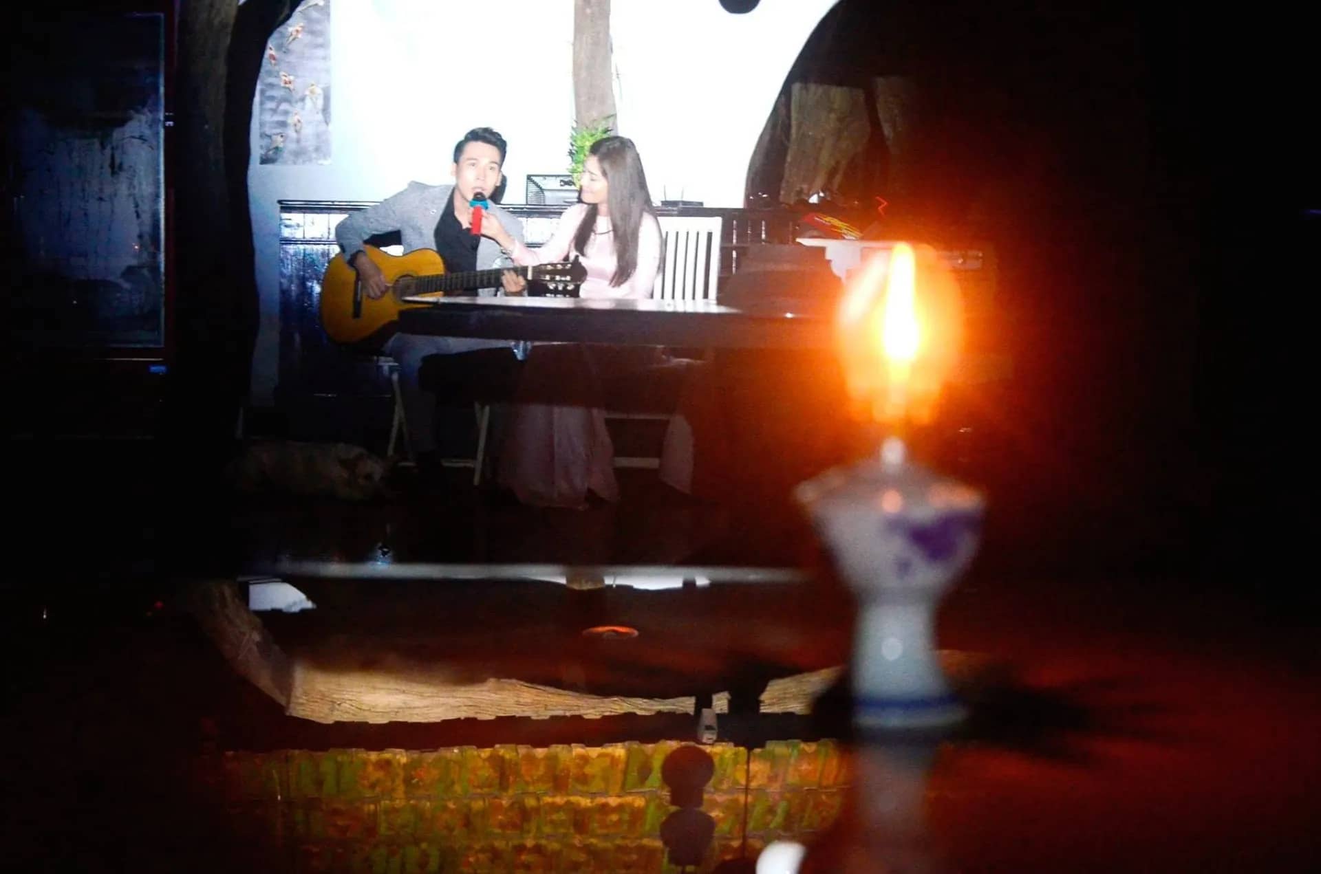 Đôi song ca ôm đàn hát, ngọn đèn dầu cháy phía trước
