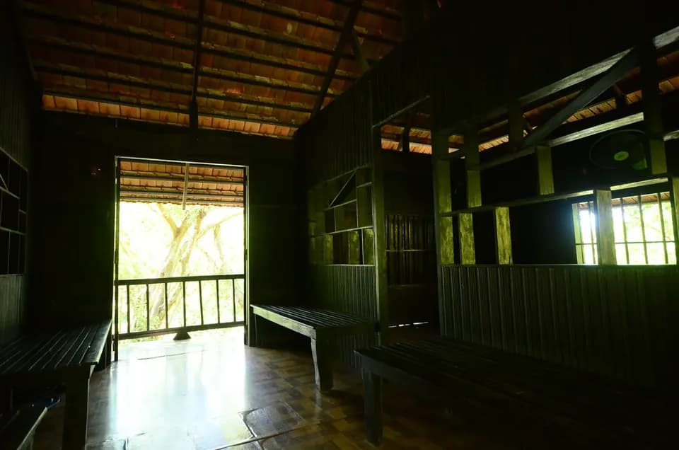 Không gian bên trong nhà sàn gỗ rộng, cửa sổ nhìn ra cây xanh