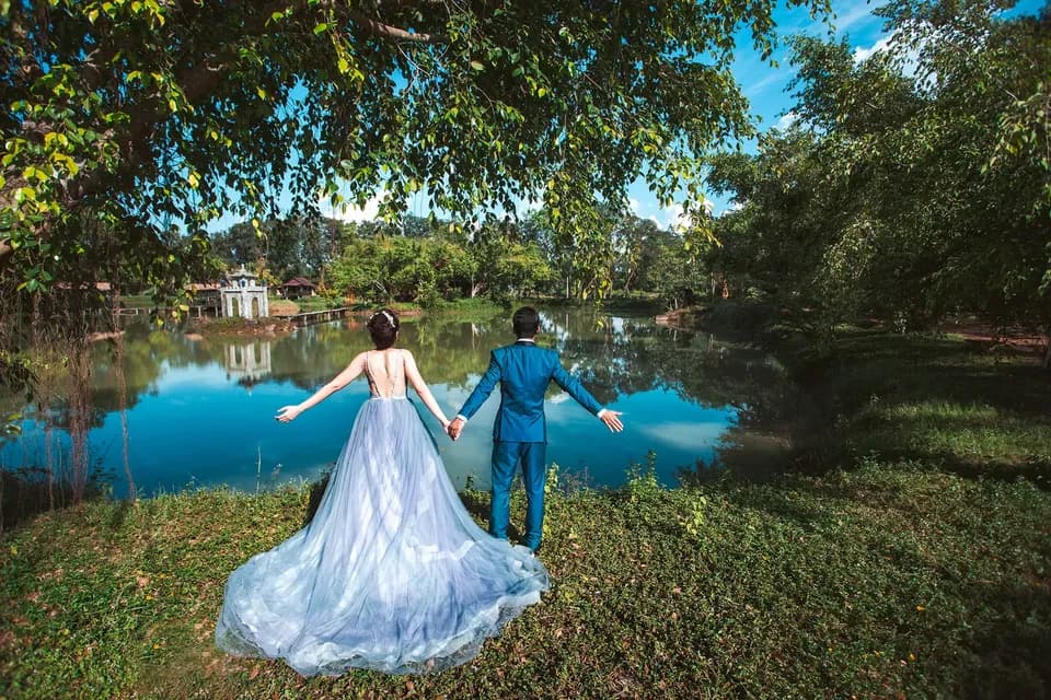 Cô dâu chú rể nắm tay nhìn ra mặt hồ, phía xa là ngôi miếu nhỏ